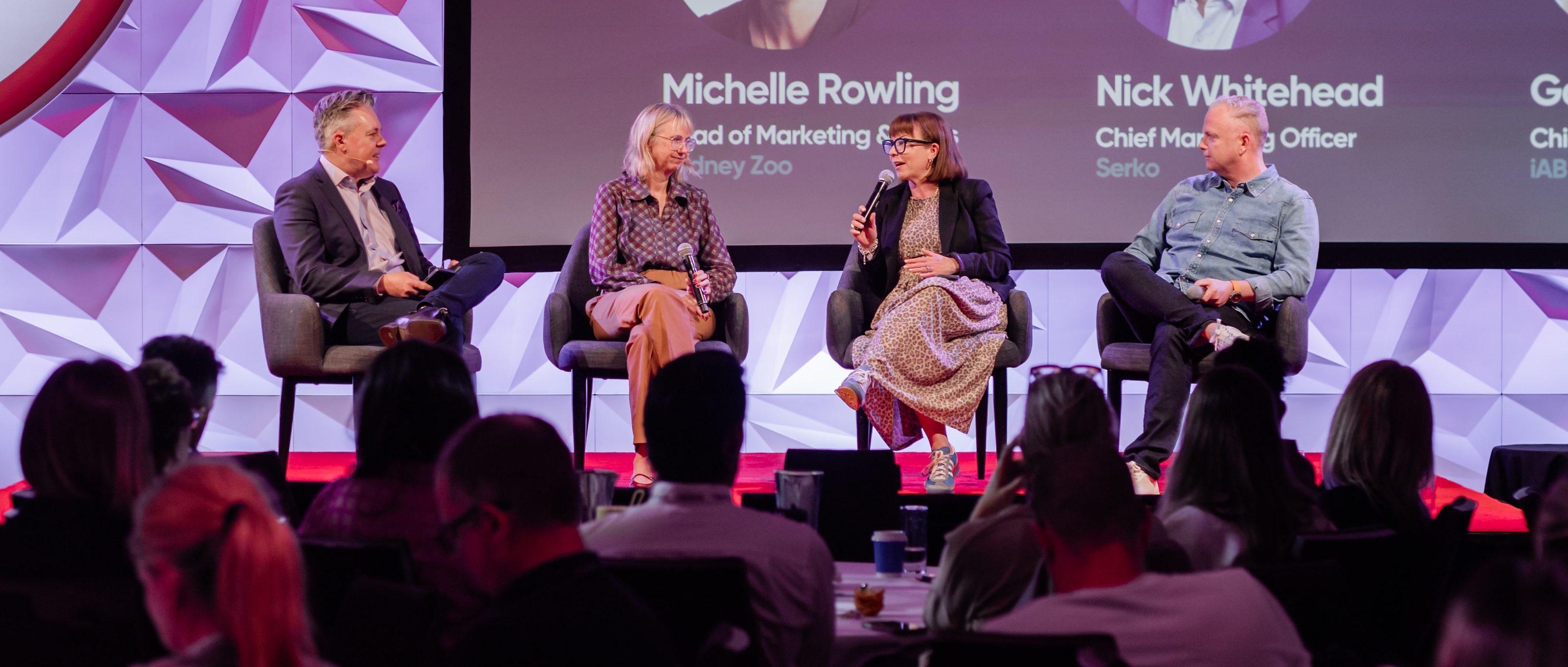 Mark Jones hosting an industry panel of three, the four of them centre stage in front of a full ballroom